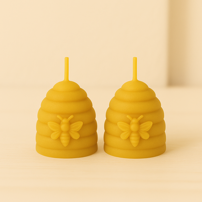 Bougies artisanales en forme de ruche avec abeille sculptée, en cire d’abeille pure, posées sur un fond beige doux.