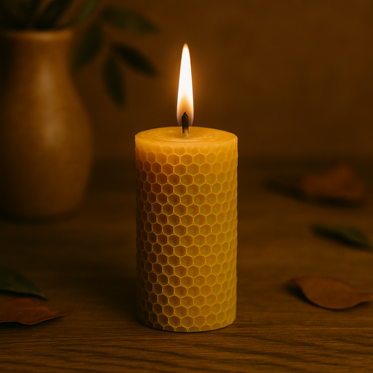 Photographie d’une bougie cylindrique en cire d’abeille gaufrée, allumée, posée sur une table en bois avec des feuilles d’automne autour, dans une ambiance naturelle et chaleureuse.