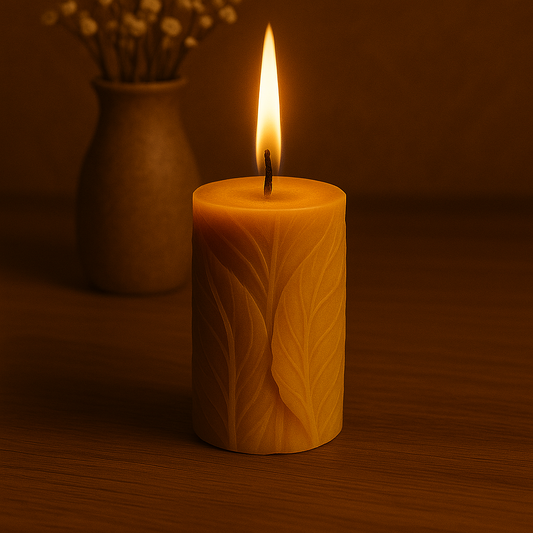 Bougie artisanale en cire d’abeille avec motif de feuilles sculptées, allumée sur une table en bois dans une ambiance chaleureuse.