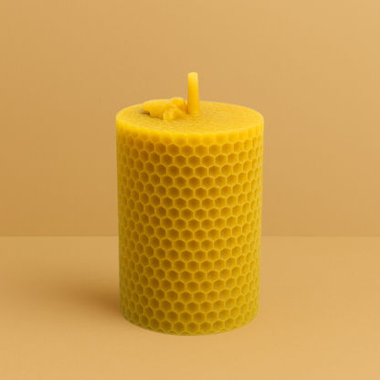 Bougie moulée 20h en cire d’abeille naturelle, avec motif alvéolé sur toute la surface, mèche épaisse centrée, posée sur un fond jaune uni.