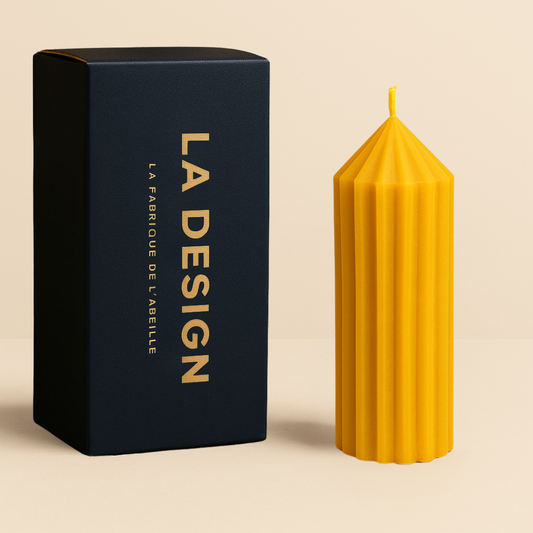 Photographie d'une bougie artisanale "La Classique" en cire d'abeille avec son étui bleu marine, sur fond beige chaleureux.