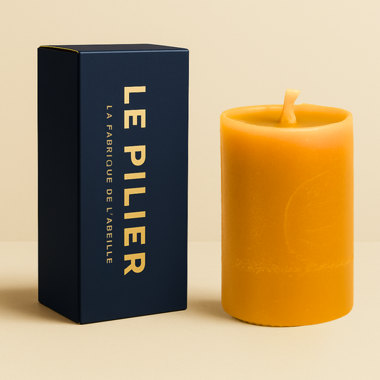 Bougie lissée en cire d'abeille, format Pilier 24h, avec packaging bleu marine "LE PILIER" doré, posée sur un fond beige.