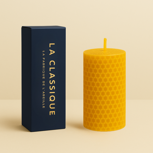 Bougie roulée en cire d'abeille, motif nid d’abeille, format 10h, accompagnée de son packaging bleu marine "LA CLASSIQUE" doré, posée sur fond beige.