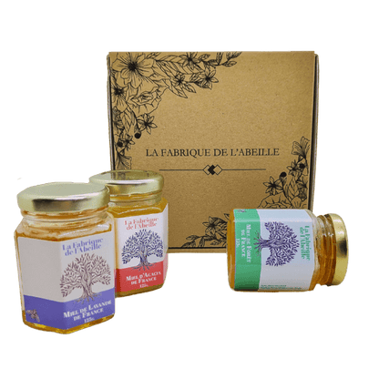 Coffret La Fabrique de l’Abeille avec trois pots de miel français : lavande, acacia et forêt, présentés devant une boîte kraft décorée